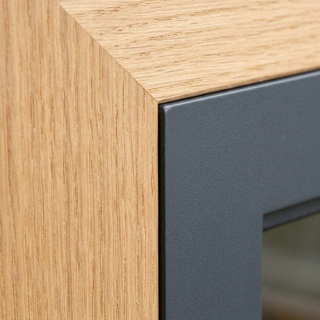 Window frame corner with an oiled oak interior lining and an aluminum exterior cap